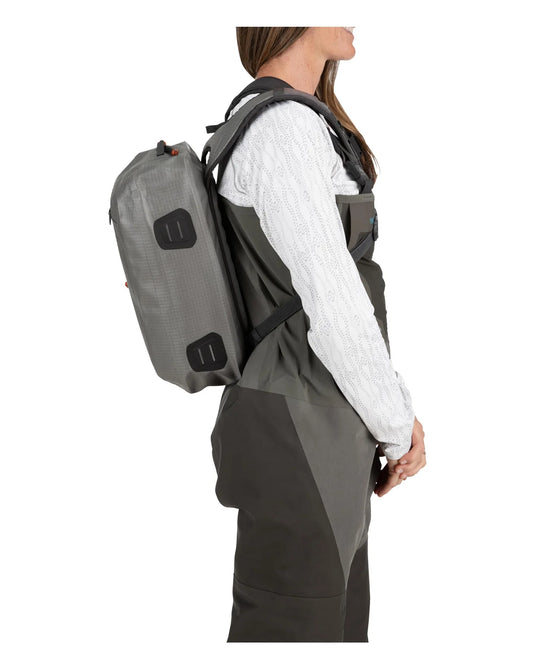 Olive-gray sling backpack worn on shoulder with back straps and logo patch