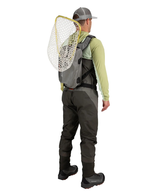 Olive-gray sling backpack worn crossbody with mesh front pocket