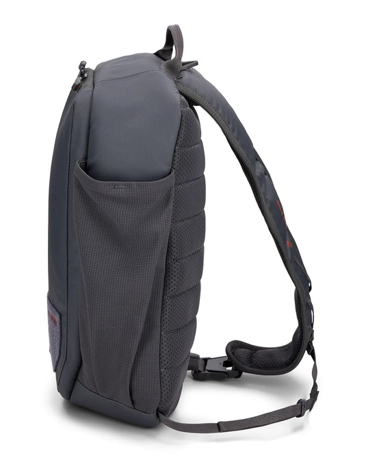 Simms Tributary sling pack, dark side view with mesh pocket and padded shoulder strap
