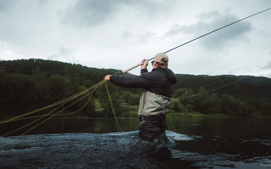 Angler holding a Spey fishing rod on a riverbank