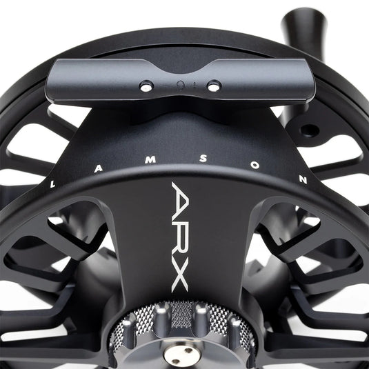 Fly fishing reel side view with engraved brand mark and knurled grip rim