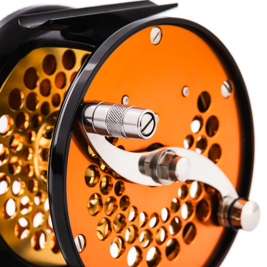 Orange fishing reel with metal handle and perforated spool face