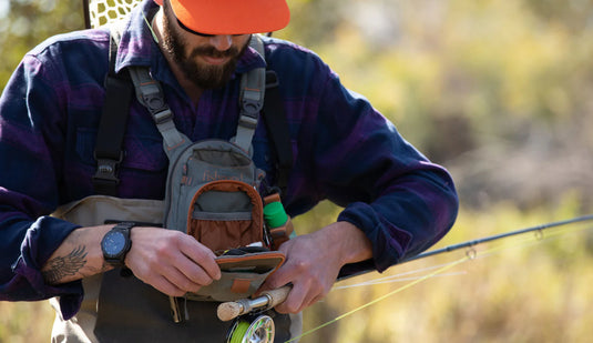 Chest pack on chest with orange-trim pocket and webbing shoulder straps