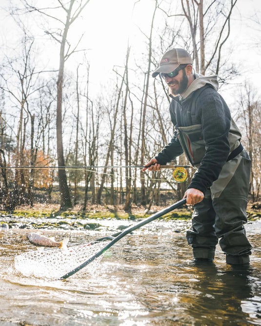 Landing net held over water with white mesh and black rim