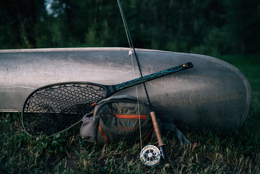 Lumbar fishing pack on grass with orange-trim pocket, gear straps, and front organizer