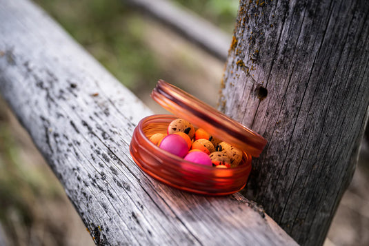 Fly puck with orange translucent lid holding colorful flies