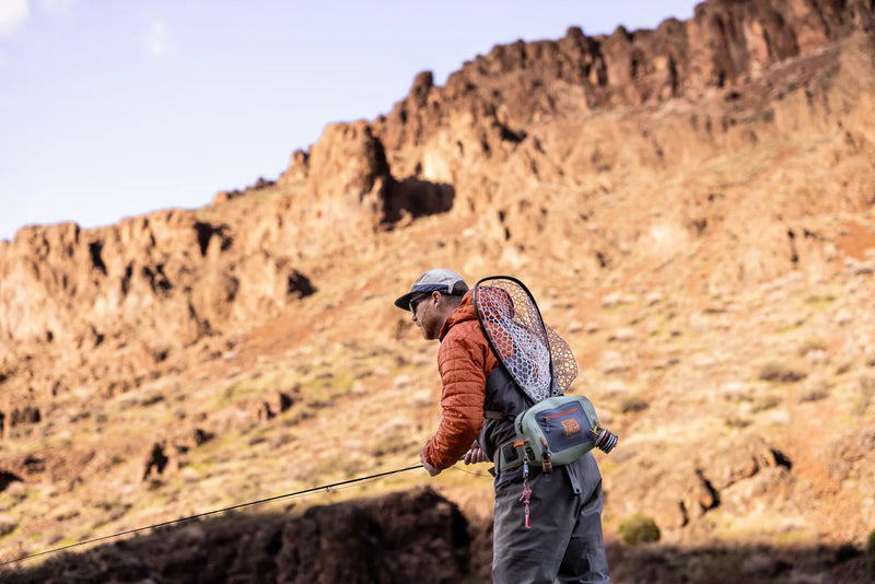 Load image into Gallery viewer, Lumbar submersible pack worn with fly-fishing gear, olive body and orange trim
