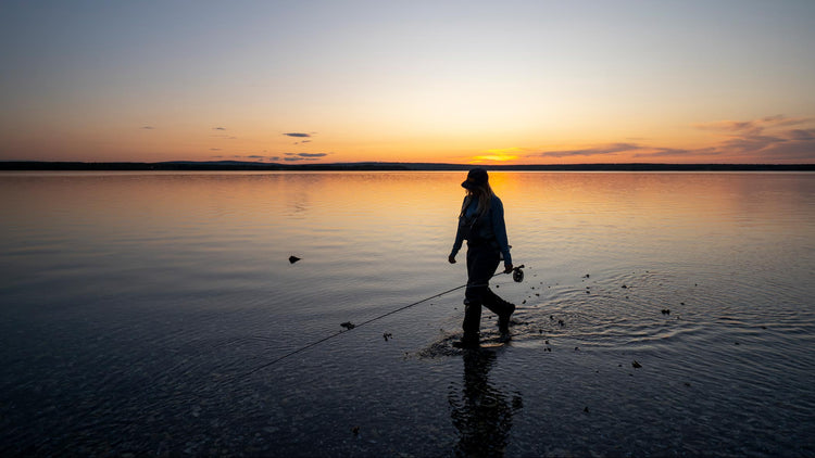 Person fishing on a lake at sunset