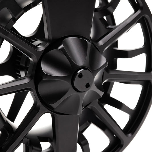 Close-up of black fly fishing reel spool with central screw and spokes