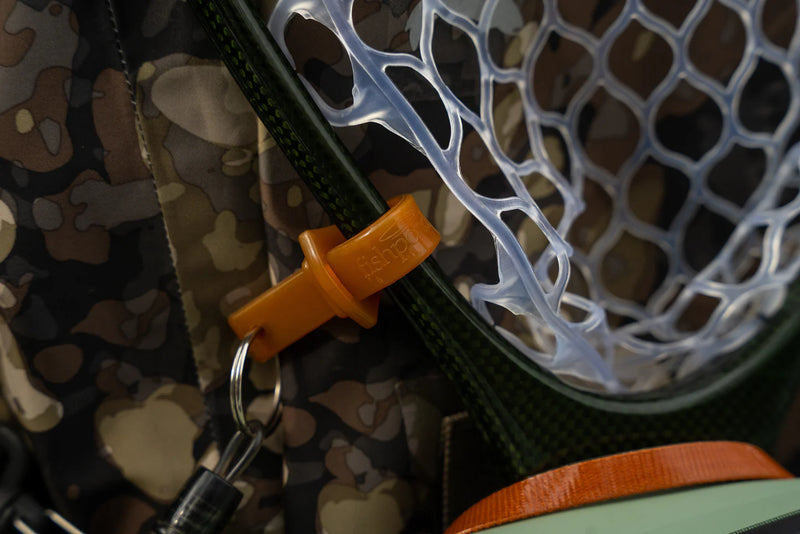 Load image into Gallery viewer, Fishing net release clip and orange latch on camo gear, attached to a white net bag
