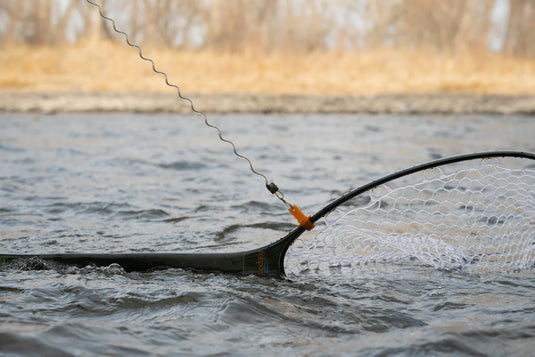 Fishing net release line with orange latch securing a white mesh net near shore