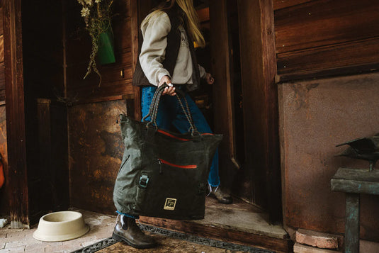 Dark green tote bag with orange-trim pocket and front logo patch, shown from above