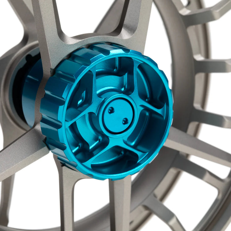 Load image into Gallery viewer, Fishing reel close-up of blue spool cover and silver spokes around it
