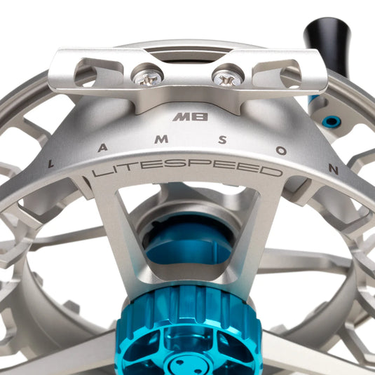 Fishing reel close-up with engraved ring and silver housing, blue spool cover below