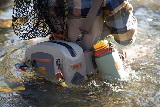 Submersible lumbar pack on water with bottle holder and orange-accented front pouch.