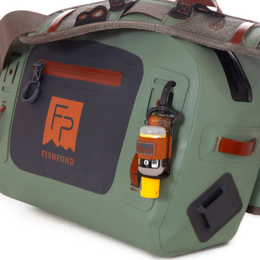 Close-up green submersible lumbar pack panel with logo, bottle clips, and carry handle.