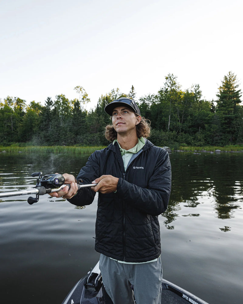 Load image into Gallery viewer, Men's dark hooded puffer jacket worn while fishing, with chest Simms logo
