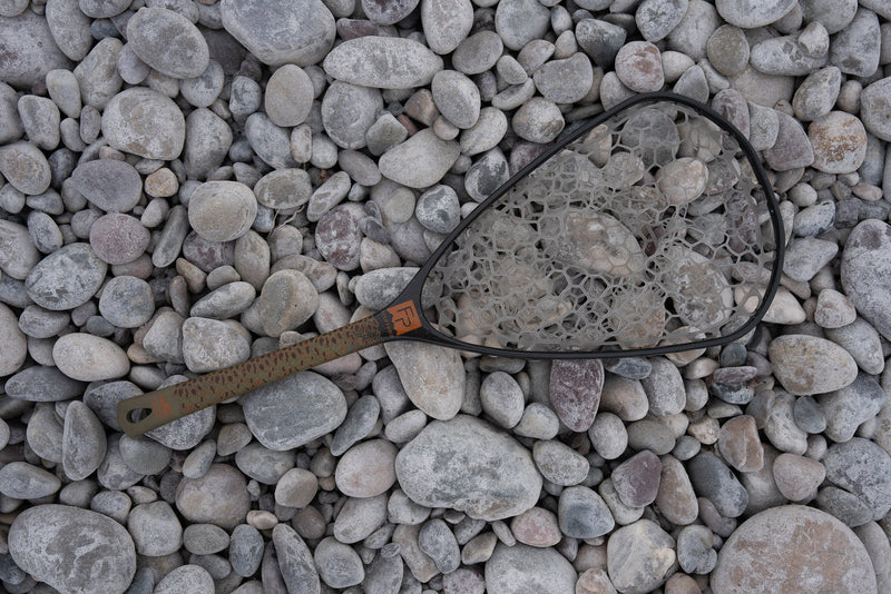 Load image into Gallery viewer, Fishing net with white mesh and dark oval frame, brown handle on gray rocks
