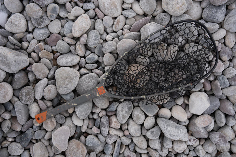 Load image into Gallery viewer, Fish landing net with black mesh and dark handle, lying on gray rocks
