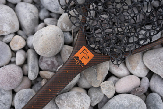 Hex-mesh landing net with brown handle and orange logo patch