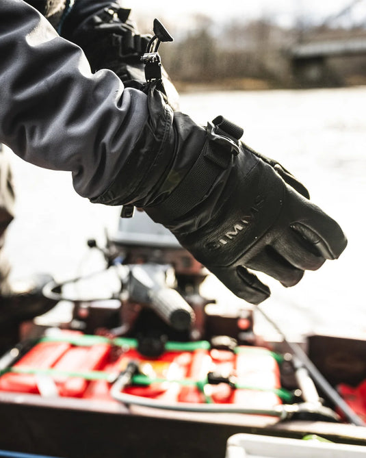 Simms insulated black glove on hand with wrist strap and pull tab
