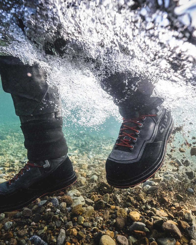 Load image into Gallery viewer, Men’s guide boot in dark gray with orange laces, worn on rocky ground in water
