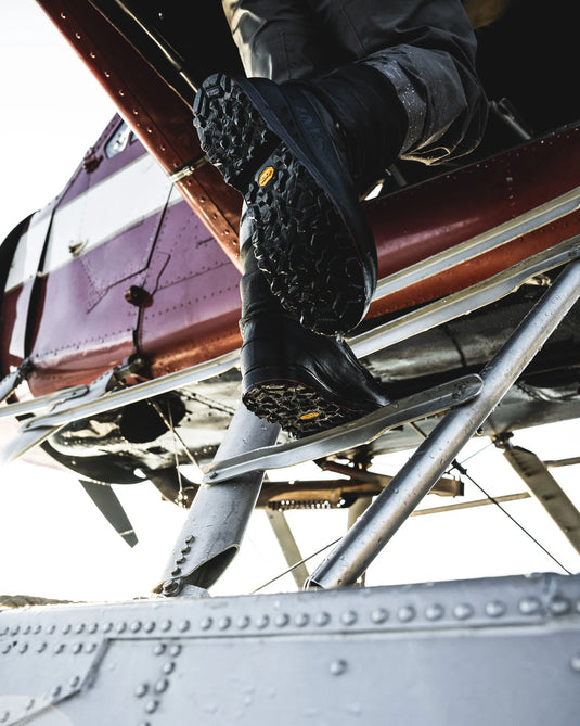 Men’s guide boot stepping on metal rails, showing black rubber sole tread