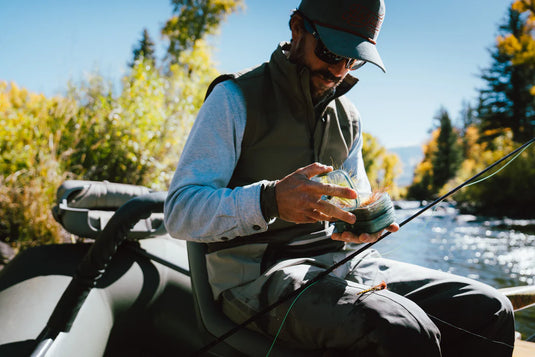 Fly fishing angler holding rod and line on a boat