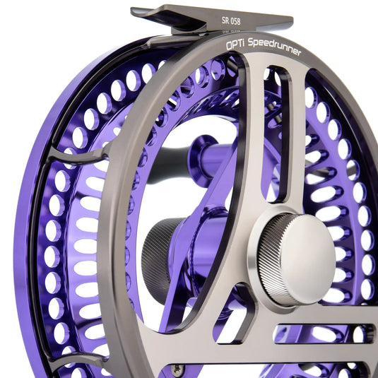 Fishing reel close-up with purple perforated rim, chrome arms, and side handle