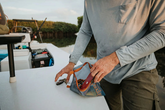Fishpond mesh travel pouch with orange zipper, held in hands