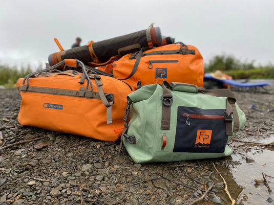 Green roll-top duffel with front logo patch, buckled strap, and side handles