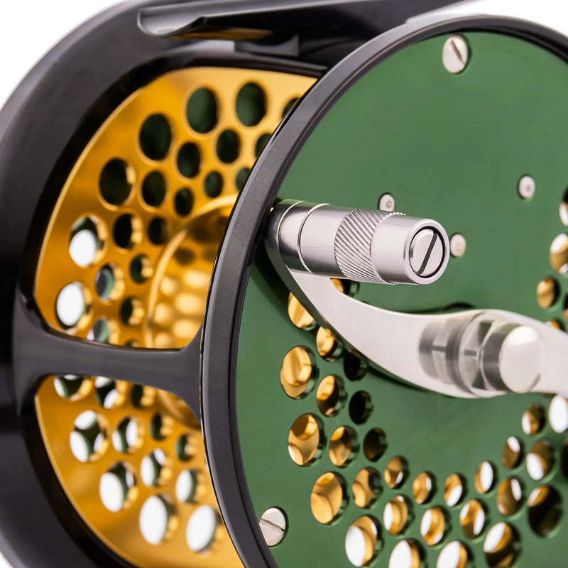 Load image into Gallery viewer, Green fishing reel with metal handle and perforated spool in gold behind it
