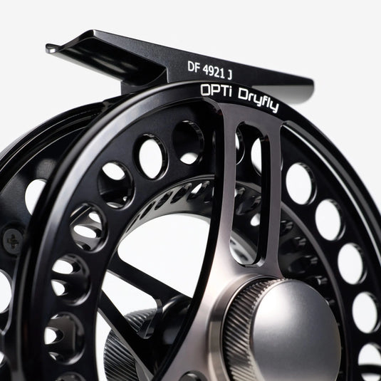 Dry-fly fishing reel, black frame with large spoke cutouts and black handle knob