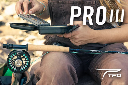 Fly fishing rod with cork handle and reel, held in hand outdoors.