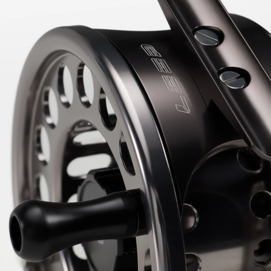Black fly fishing reel close-up with handle knob and metal spool edge