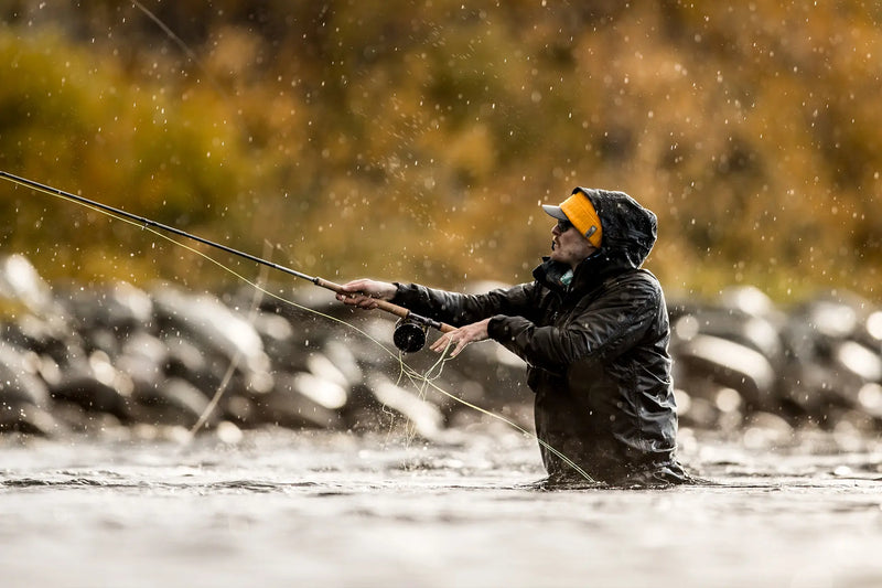 Load image into Gallery viewer, Angler holding a double-handed fishing rod with line cast over water
