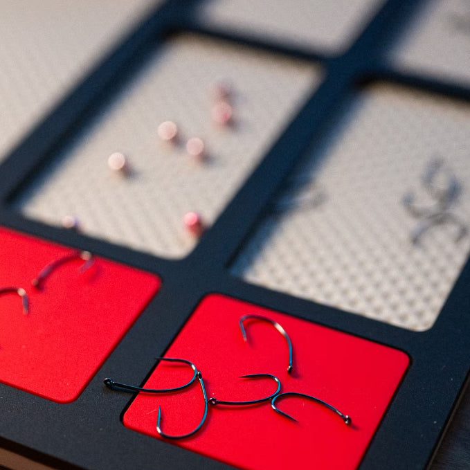 Load image into Gallery viewer, Fly tying mat with red hook-holding sections in a dark frame
