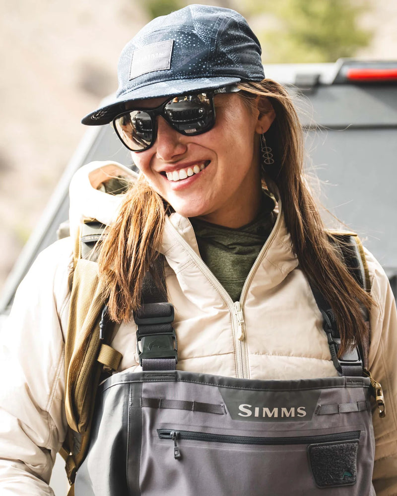 Load image into Gallery viewer, Simms cap on model, dark speckle print with curved brim and logo patch
